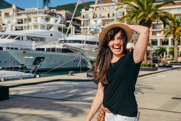 Lächelndes Frauenporträt am Dock mit Yachten im Hintergrund Sommerzeitkonzept