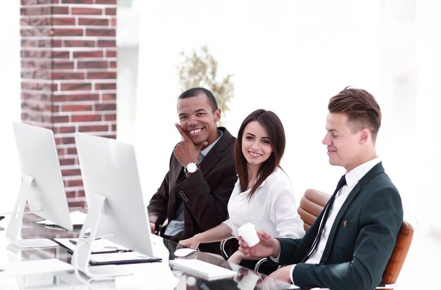 Lächelndes Geschäftsteam, das am Schreibtisch im modernen Büro sitzt