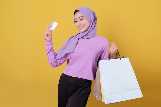 Lächelndes glückliches hübsches Mädchen, das Kreditkarte benutzt, um etwas Geld im Einkaufszentrum zu verschwenden, Einkaufstaschen zu halten, Geschenke oder Geschenke zu kaufen, gönnen Sie sich Tag