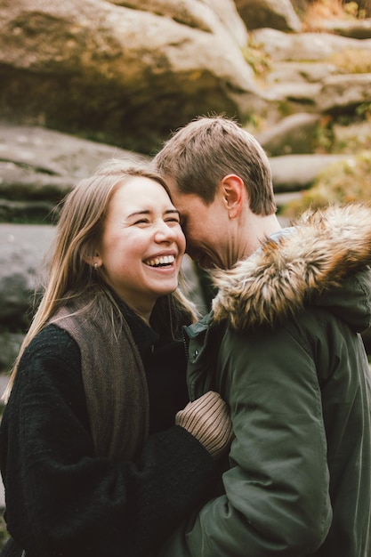 Lächelndes heterosexuelles Paar steht gegen einen Felsen