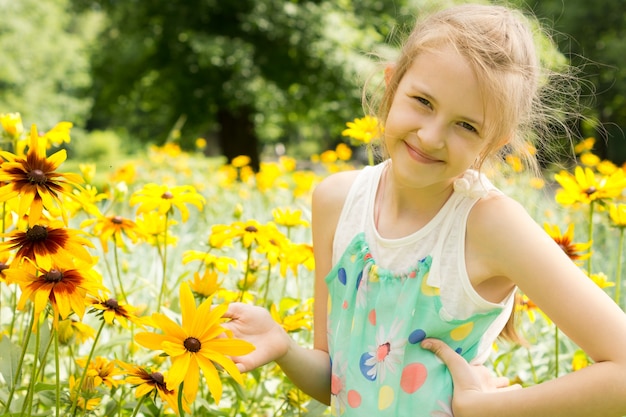 Lächelndes junges Mädchen, das in gelben Blumen spielt