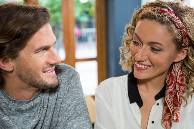 Lächelndes junges Paar, das einander im Kaffeehaus ansieht