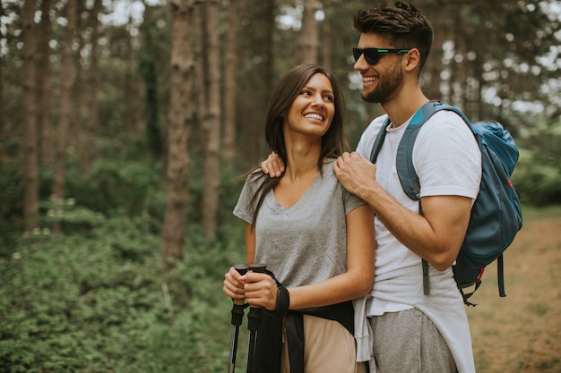 Lächelndes junges Paar, das mit Rucksäcken im Wald geht