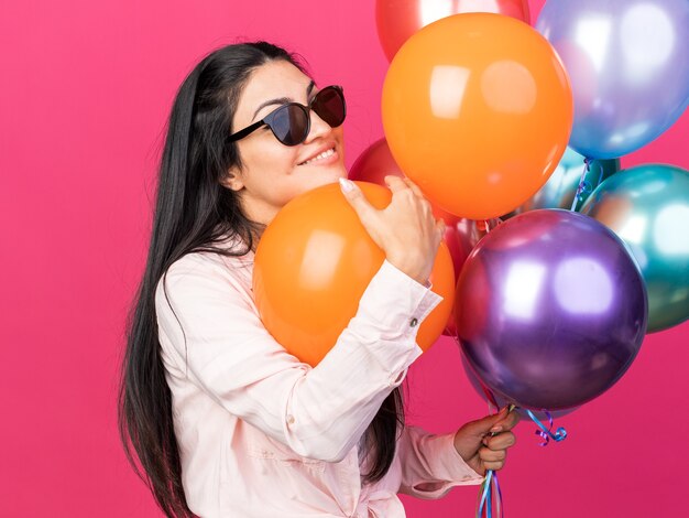 Lächelndes junges schönes Mädchen mit Brille mit Ballons