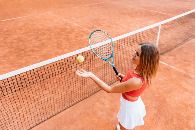 Lächelndes junges sportliches Mädchen, das Tennis spielt