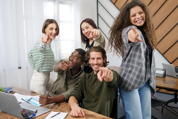 Lächelndes junges Team in einem Coworking, das auf Sie zeigt, Nahaufnahme