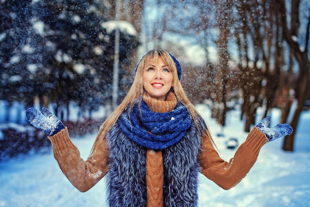 Foto lächelndes kaukasisches mädchen, das am sonnigen wintertag schnee in die luft wirft emotionale junge glückliche frau