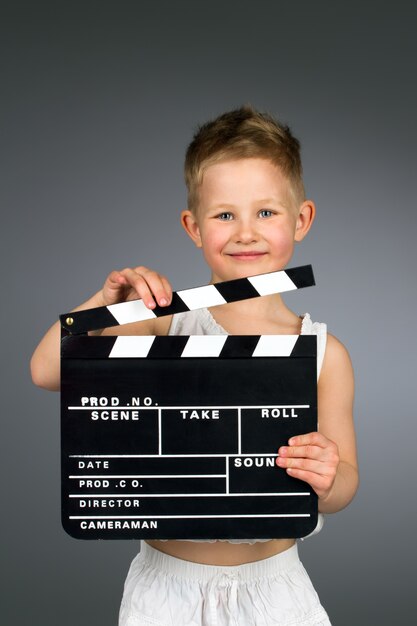 Lächelndes Kind, das Filmklappe hält.