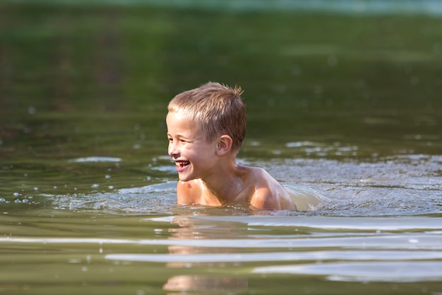 lächelndes Kind, das im schlammigen Wasser am sonnigen Tag schwimmt