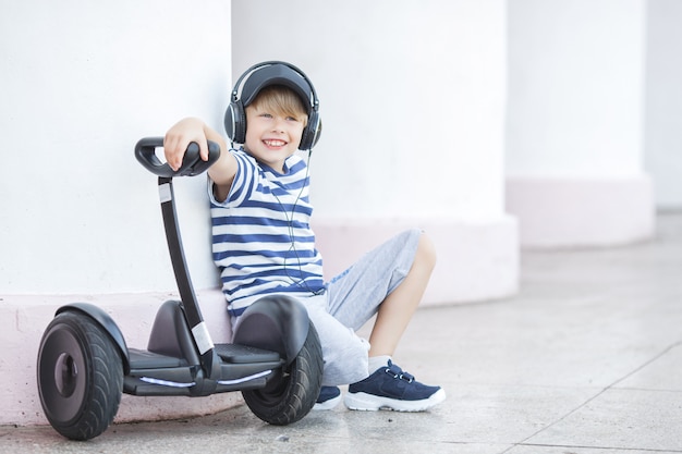 Lächelndes Kind, das Segway reitet. Aktive Jugend. Netter Junge draußen mit elektrischem Rover.