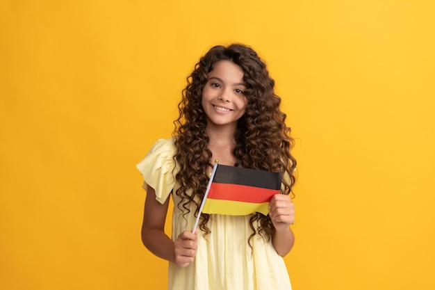 Lächelndes Kind mit langen lockigen Haaren hält die deutsche Flagge Deutschland