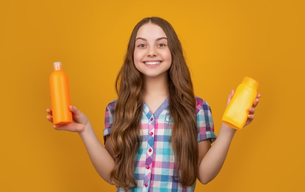 Lächelndes Kind mit Shampooflasche auf gelbem Hintergrund