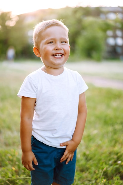 Lächelndes Kind mit Spielzeug im Sommerpark an einem sonnigen Tag Süßer kleiner Junge, der frisches Frühlingswetter genießt