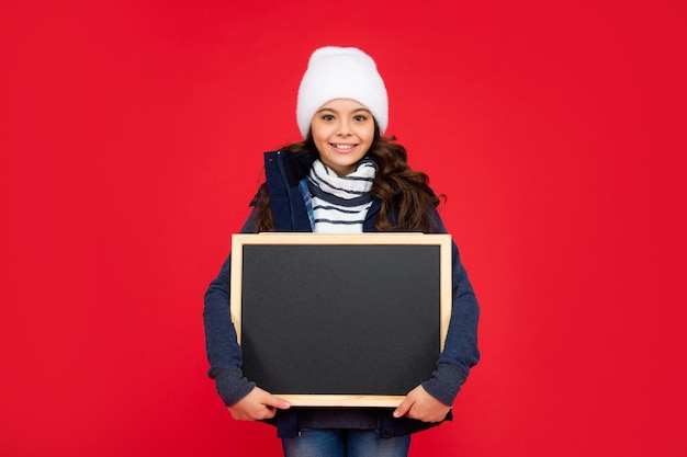 Lächelndes Kind zurück zur Schulankündigung und Werbung Winterschlussverkauf Kind halten Tafel