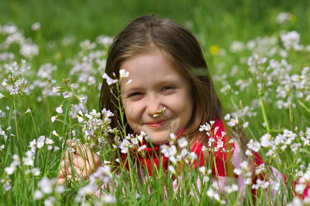 Lächelndes Kindermädchen, das auf einem Gras an der Wiese liegt.