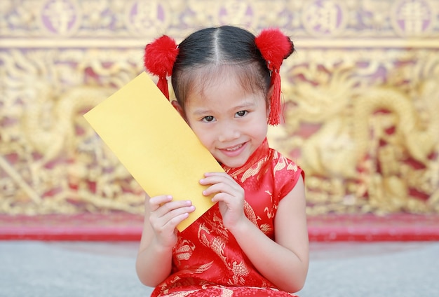 Lächelndes kleines asiatisches Mädchen, das Goldumschlag hält