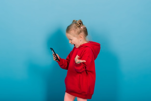 Lächelndes kleines Mädchen am Telefon über blauem Hintergrund