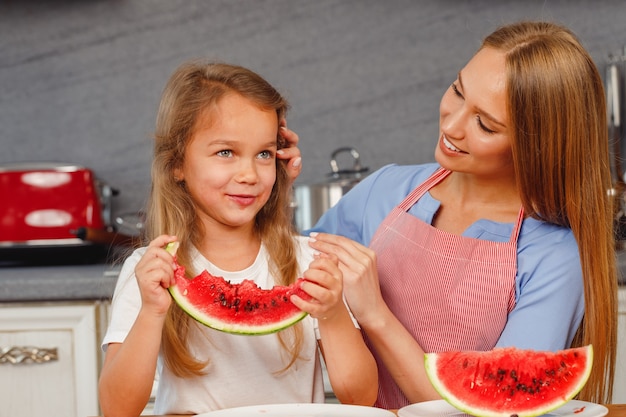 Lächelndes kleines Mädchen, das eine Scheibe Wassermelone in der Küche isst