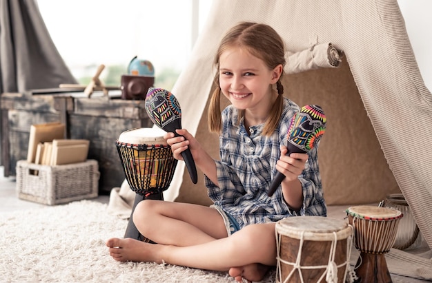 Lächelndes kleines Mädchen, das Musik-Maracas schüttelt