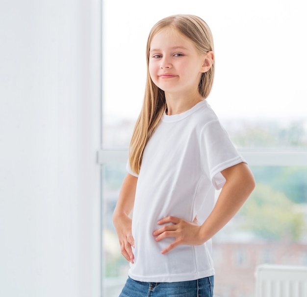 Lächelndes kleines Mädchen, das vor Fenster aufwirft