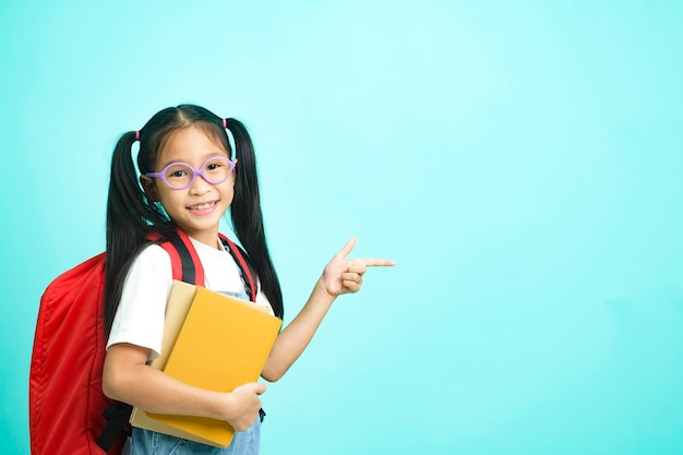 Lächelndes kleines Mädchen mit Brille, das mit dem Finger nach oben zeigt