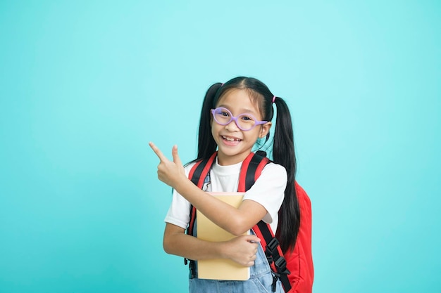 Lächelndes kleines Mädchen mit Brille, das mit dem Finger nach oben zeigt