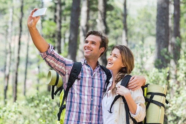 Lächelndes klickendes selfie der Paare bei der Stellung im Wald