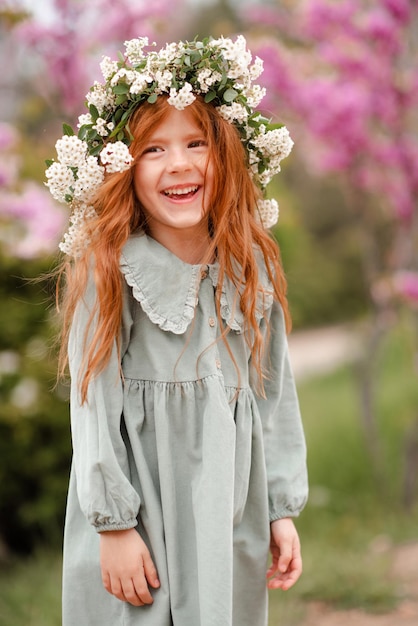 Lächelndes, lachendes Mädchen mit Blumenkranz mit Blumen im Freien