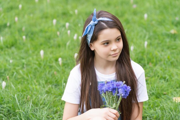 Lächelndes Mädchen auf Gras mit Frühlingsblumen kopieren Raum