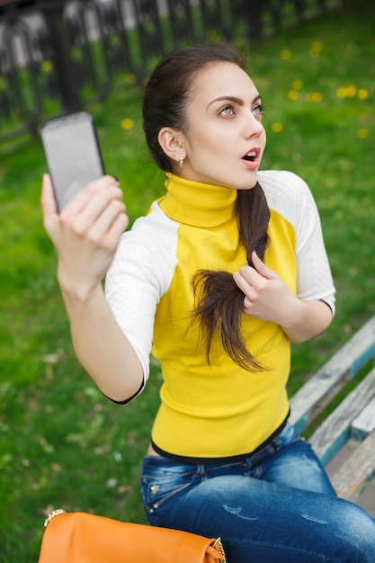 Lächelndes Mädchen, das Bild mit Smartphone-Kamera im Freien macht. Selfie