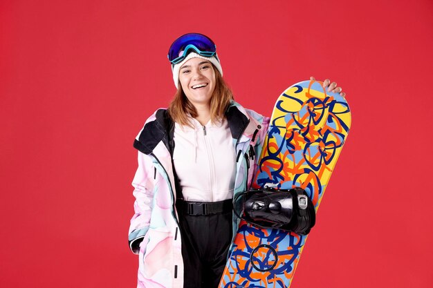 Lächelndes Mädchen, das die Kamera mit einem Snowboard untersucht