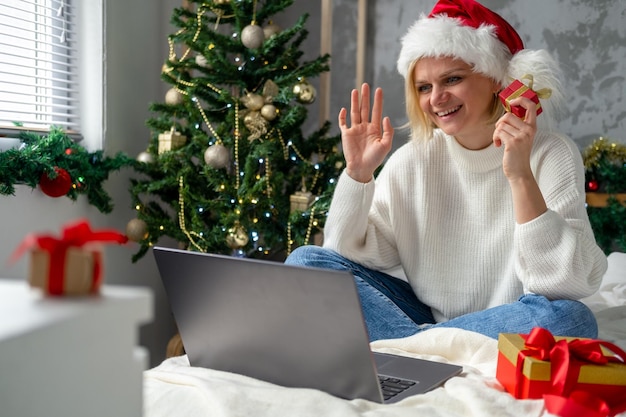 Foto lächelndes mädchen, das ein laptop-notebook für videoanrufe mit freunden und eltern verwendet weihnachts-online-familienglückwünsche