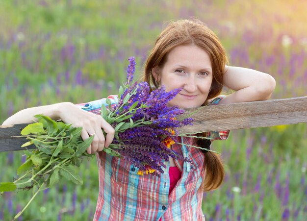 Lächelndes Mädchen, das einen Blumenstrauß an den Feldern hält