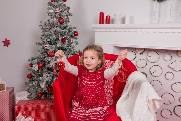 Lächelndes Mädchen, das Verzierungen hält. Weihnachtsfeier.