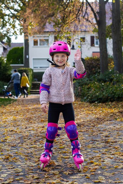 Lächelndes Mädchen in einem Helm in Schutzrollschuhen im Park