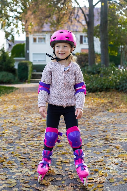 Lächelndes Mädchen in einem Helm in Schutzrollschuhen im Park