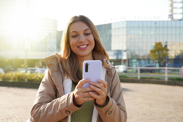 Lächelndes Mädchen in Winterkleidung mit Telefon in der Stadt