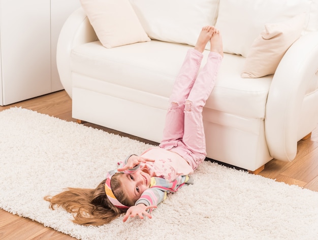 Lächelndes Mädchen streckt sich im Wohnzimmer