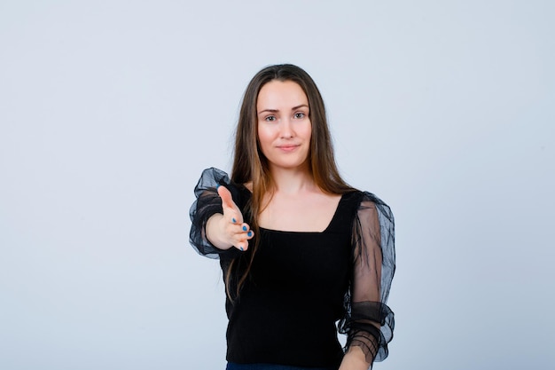 Lächelndes Mädchen zeigt hallo Geste, indem es die Hand zur Kamera auf weißem Hintergrund ausstreckt