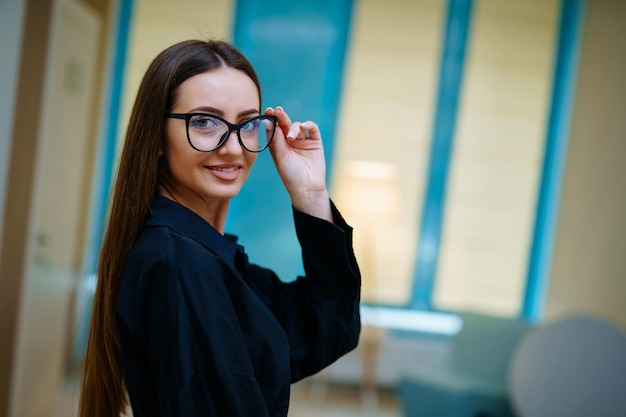 Lächelndes nettes Mädchen schaut in die Kamera und trägt eine moderne Brille Frau in Brille präsentiert Produkt der Kamera Nahaufnahme