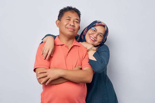 Lächelndes Paar asiatische Frau Mann 50er Jahre stehen umarmt und suchen Kamera mit lächelndem Gesichtsausdruck und glücklich isoliert auf weißem Hintergrund Studioportrait