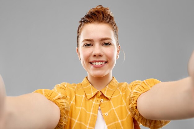 Foto lächelndes rothaariges teenager-mädchen macht ein selfie