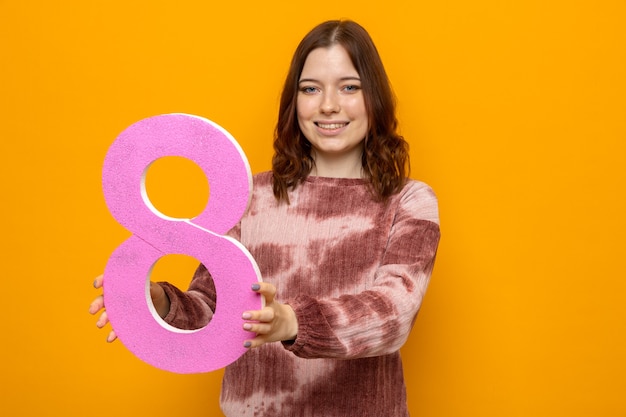 Lächelndes schönes junges Mädchen am glücklichen Frauentag, der Nummer acht heraushält