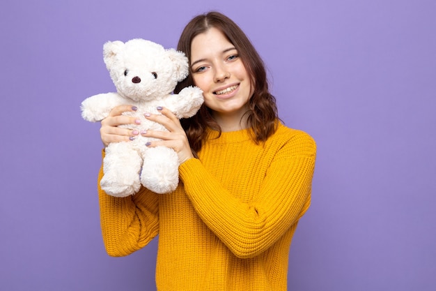 Lächelndes schönes junges Mädchen, das Teddybären hält