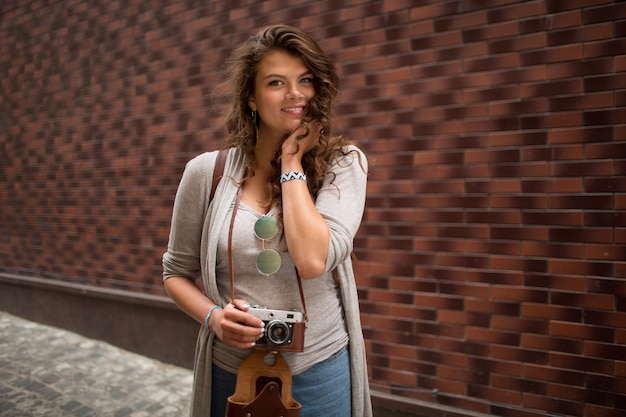 Lächelndes schönes touristisches Mädchen, das für Kamera in der Straße aufwirft.