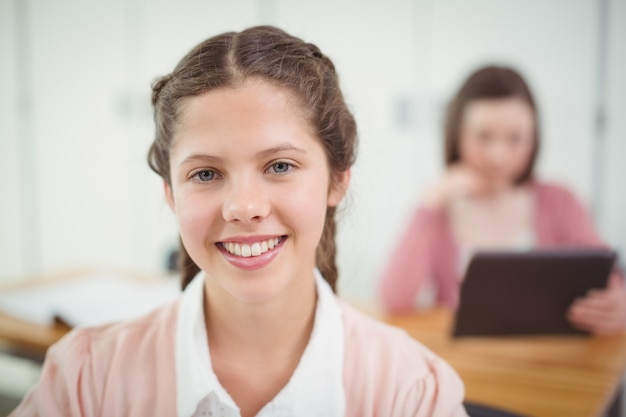 Lächelndes Schulmädchen, das im Klassenzimmer sitzt