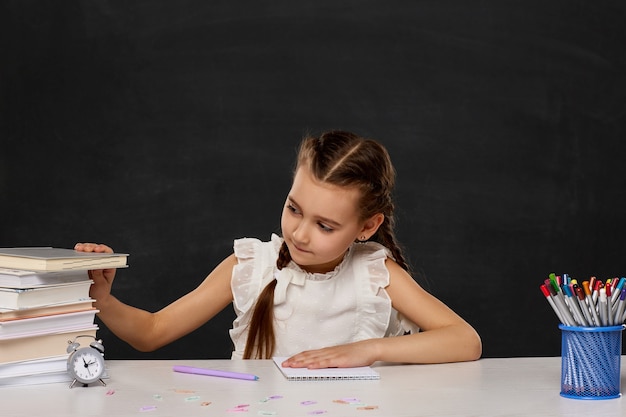 Lächelndes Schulmädchen, das mit einem Stapel Büchern studiert