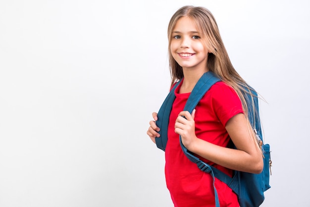 Foto lächelndes schulmädchen, das mit rucksack steht