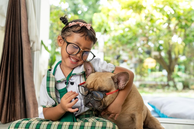 Lächelndes Schulmädchen, das zu Hause mit ihrer französischen Bulldogge spielt