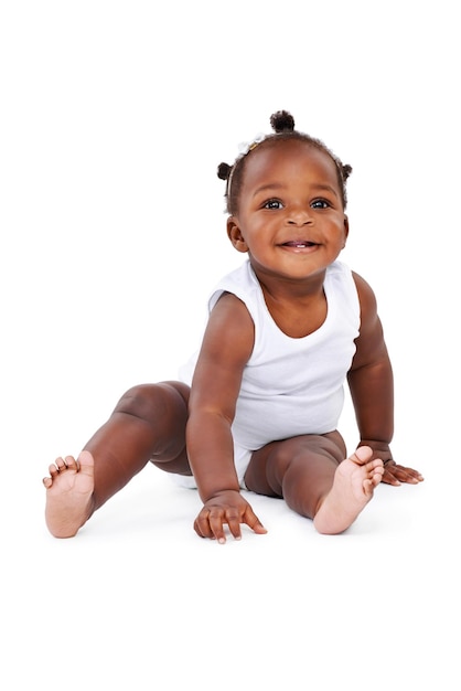 Lächelndes Sitzen und afrikanisches Mädchenbaby isoliert auf weißem Hintergrund mit spielerischem Glück und Wachstum. Lernen, Spielen und Lachen eines glücklichen schwarzen Kindes vor Studiohintergrund für Entwicklung und Kinderbetreuung